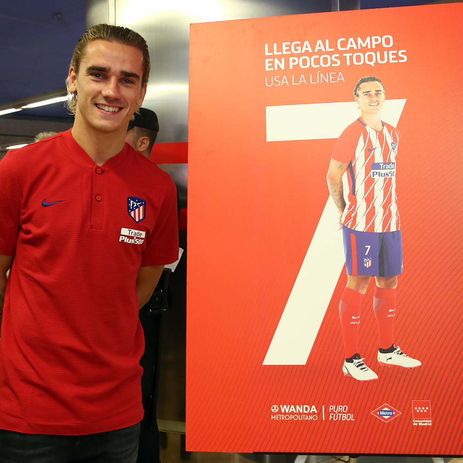 Griezmann posa junto al cartel que anima a los aficionados a llegar al Wanda Metropolitano por la línea 7