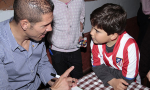 Simeone firma un autógrafo a un niño en la peña Cholo Simeone