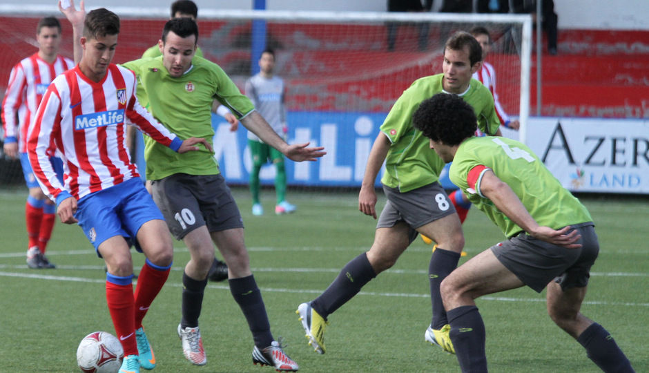 Ian, jugador del Atlético C, conduce el esférico ante varios jugadores del Adarve