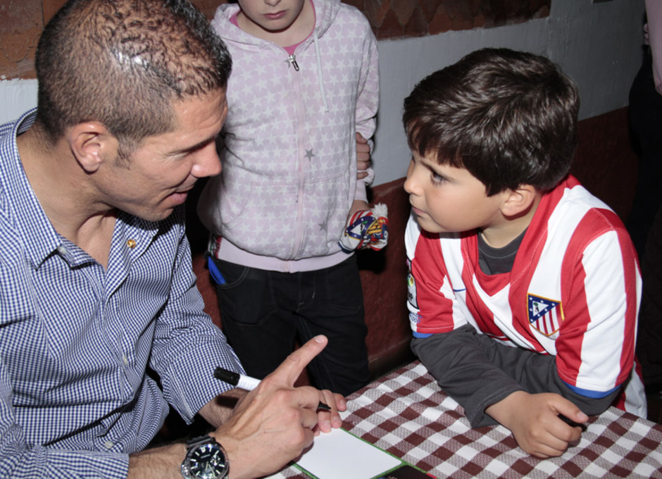 Simeone firma un autógrafo a un niño en la peña Cholo Simeone