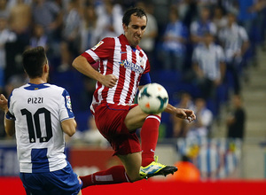 Godín se lanza a por el balón ante la presencia de un jugador del Espanyol