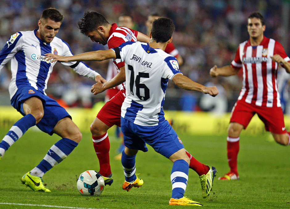 David Villa regateando a dos jugadores del Espanyol