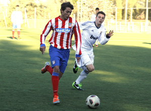 Liga 2012-2013. Un jugador del Juvenil A ante un defensa del Real Madrid durante el derbi jugado en la Ciudad Deportiva de Majadahonda.